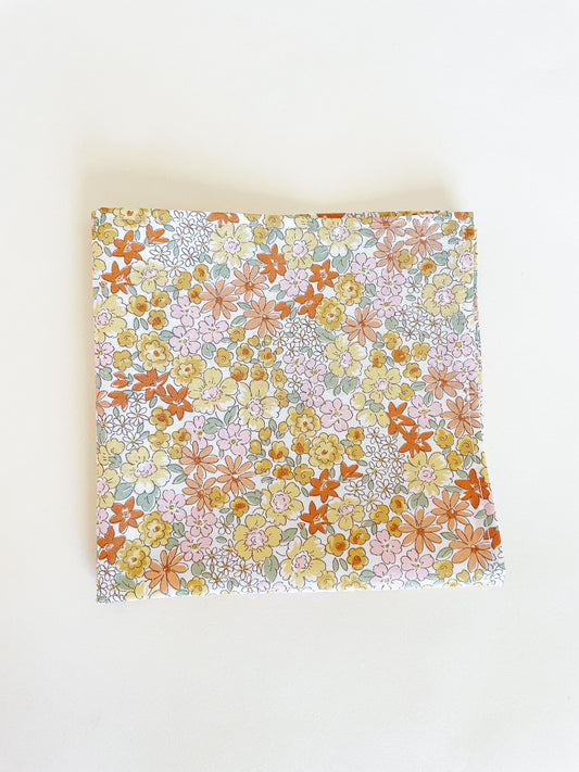 A handmade pocket square with yellow flowers against an off white background.