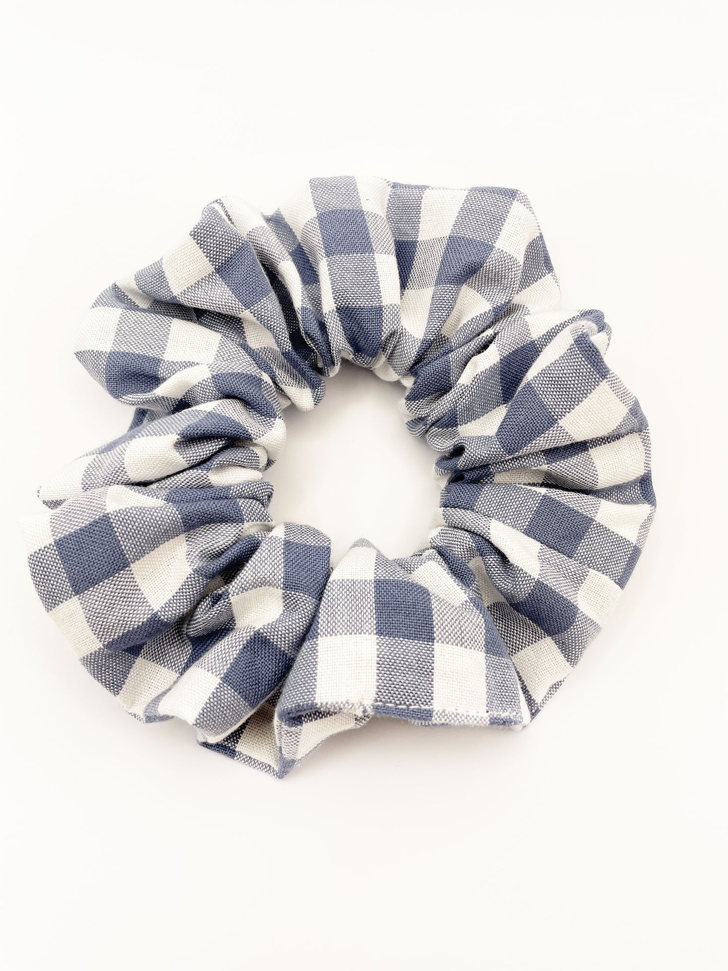 A handmade slate blue gingham plaid scrunchie against an off white background.