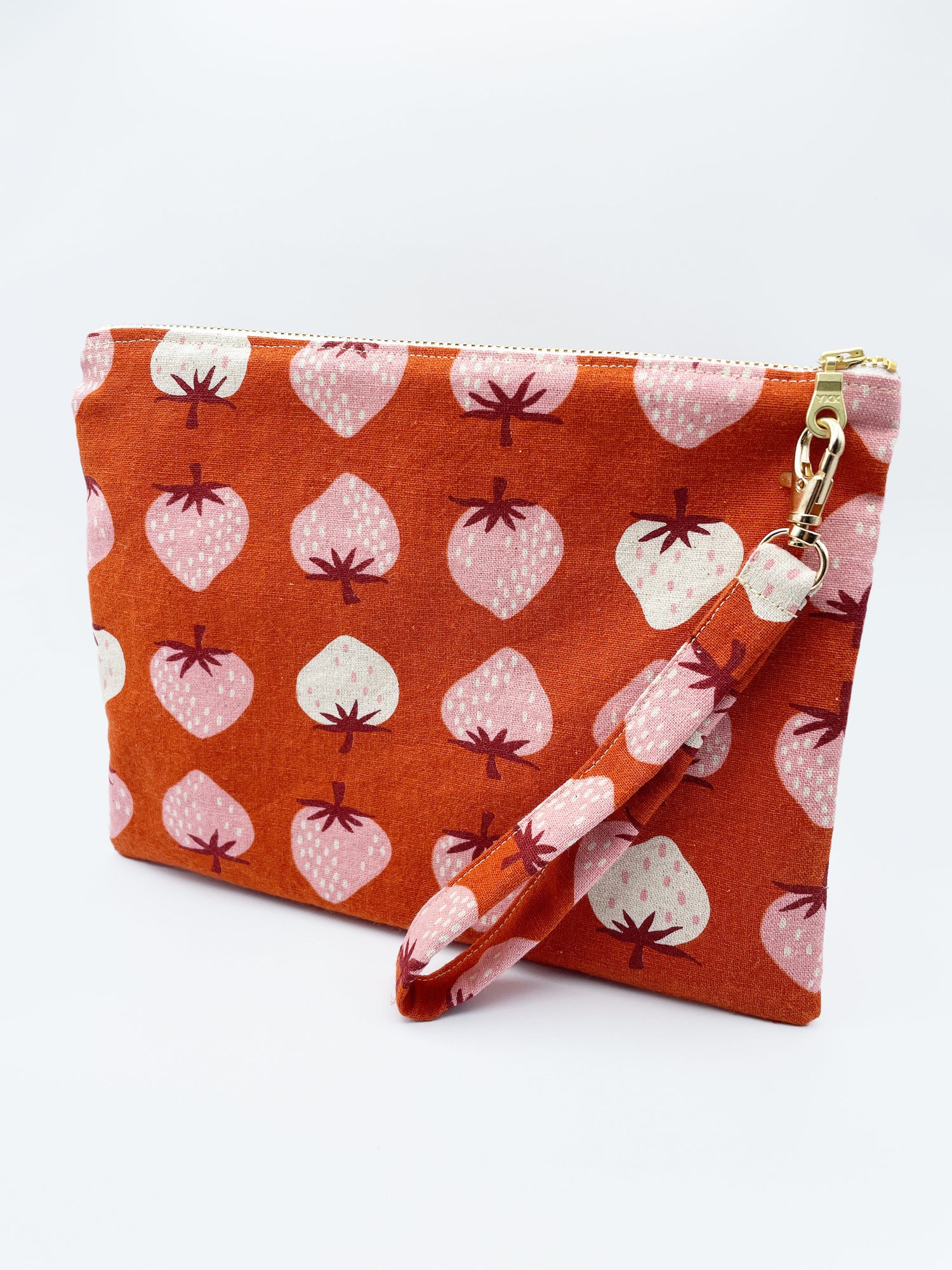 A handmade red zippered pouch with pink and white strawberries.