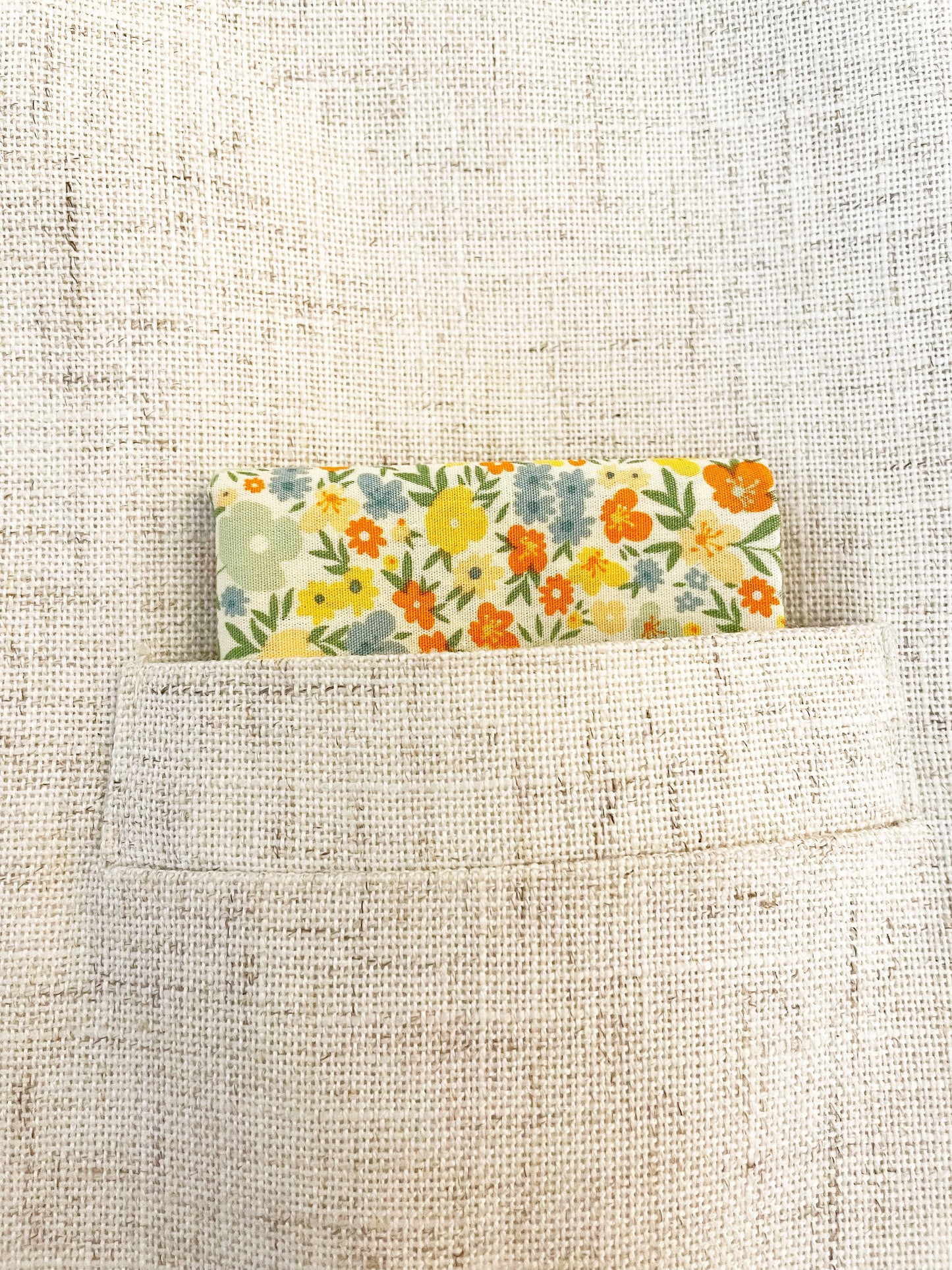 A handmade pocket square featuring colorful flowers shown in the pocket of a suit jacket.