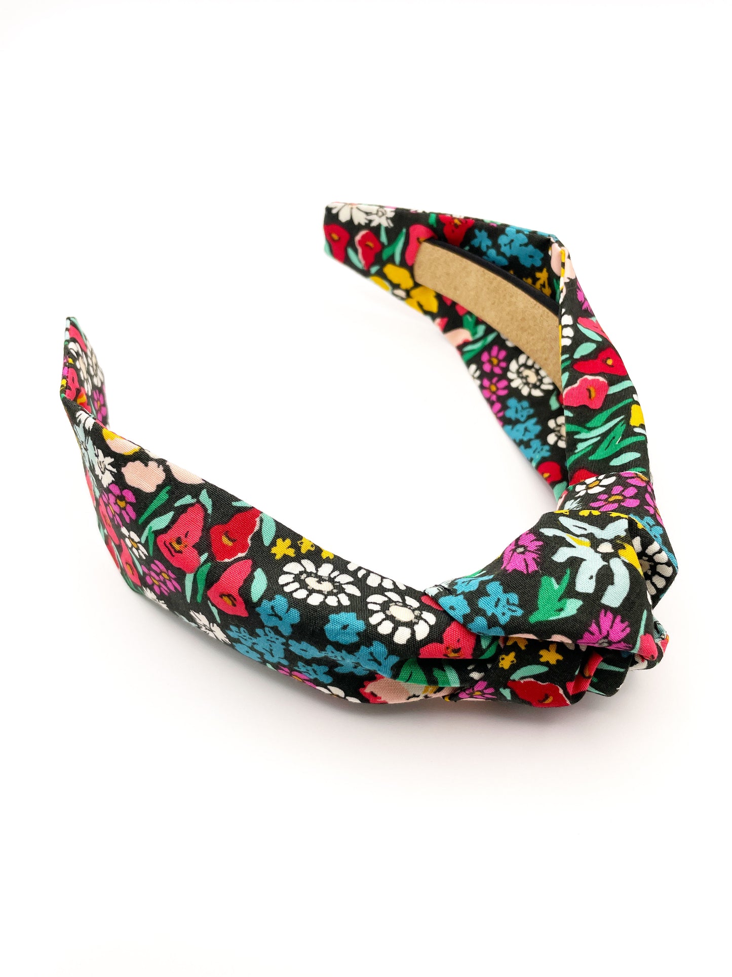 A black handmade knotted headband with a colorful floral print.