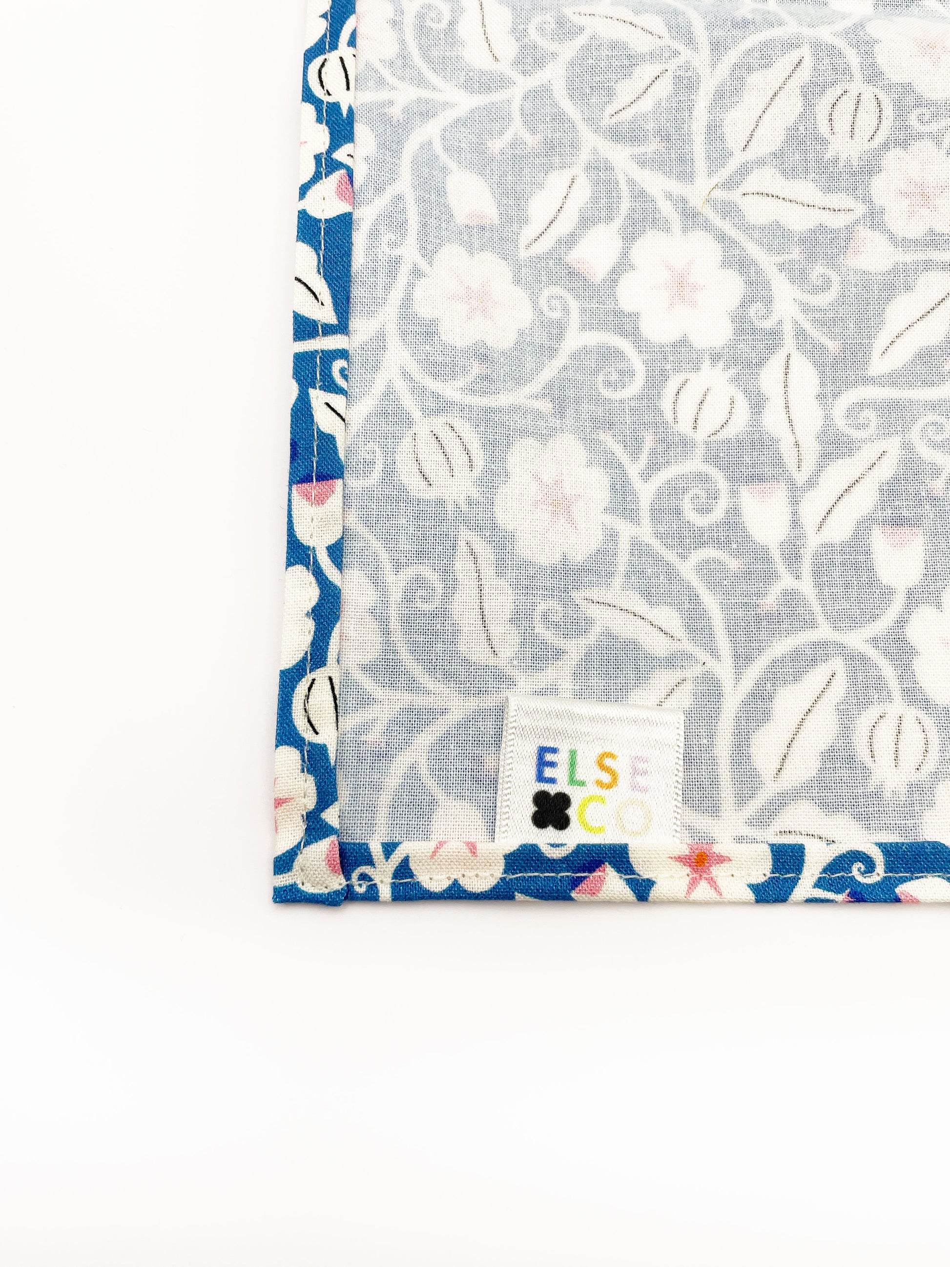 A blue pocket square with white flowers that have pink centers.