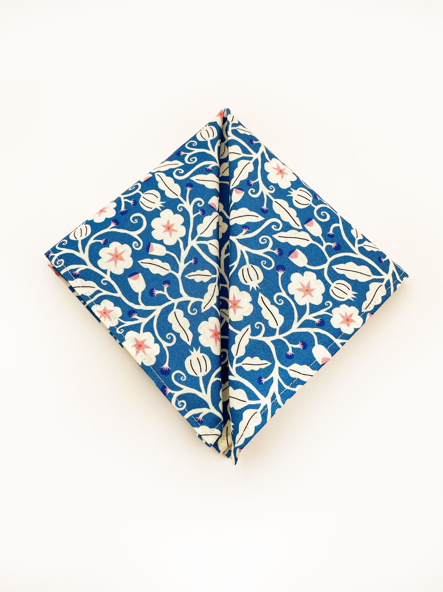 A blue pocket square with white flowers that have pink centers.