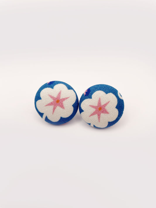Handmade blue fabric-covered earrings with white flowers that have pink centers.