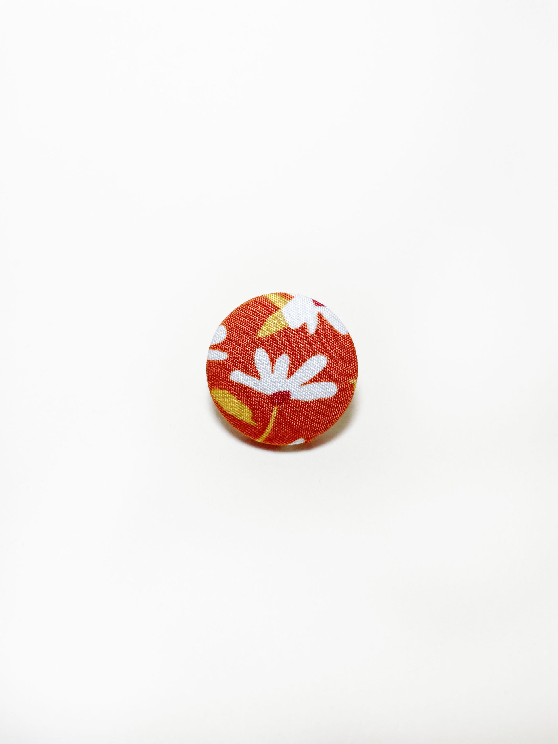 Handmade rust colored floral fabric covered lapel pin.