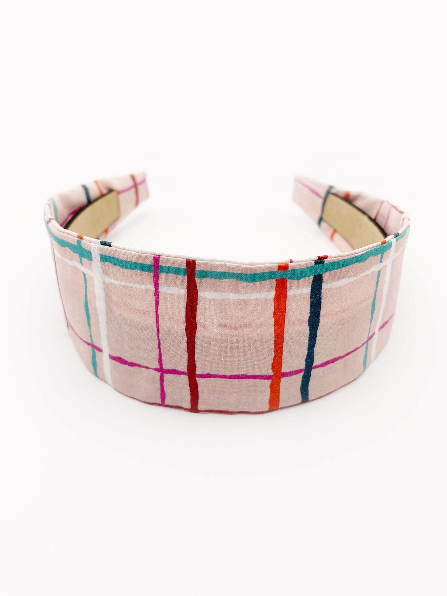 A fabric headband featuring a colorful and modern plaid design with vibrant shades of pink, red, teal, and orange on a soft pastel background.