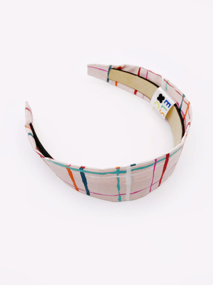 A fabric headband featuring a colorful and modern plaid design with vibrant shades of pink, red, teal, and orange on a soft pastel background.