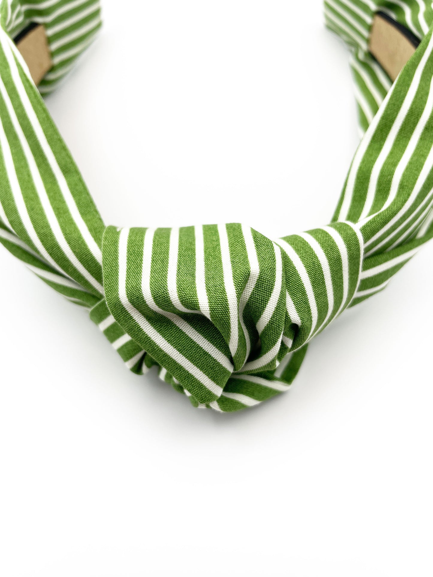 A handmade knotted headband featuring a white striped print against a moss green background.