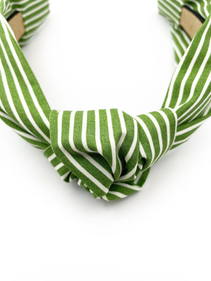 A handmade knotted headband featuring a white striped print against a moss green background.