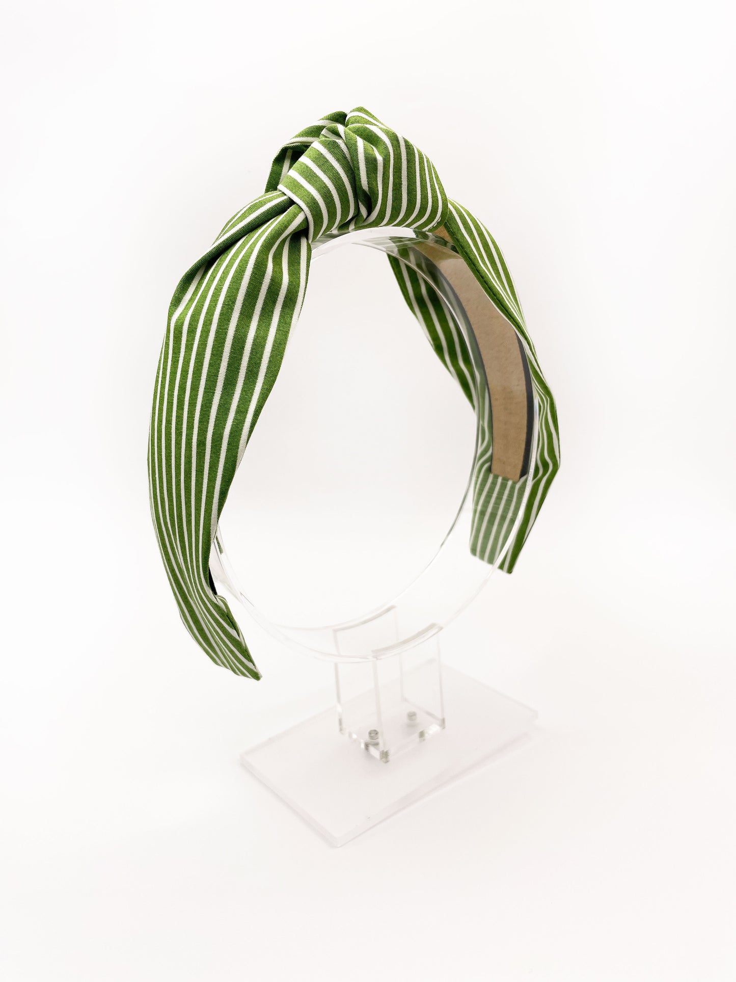 A handmade knotted headband featuring a white striped print against a moss green background.