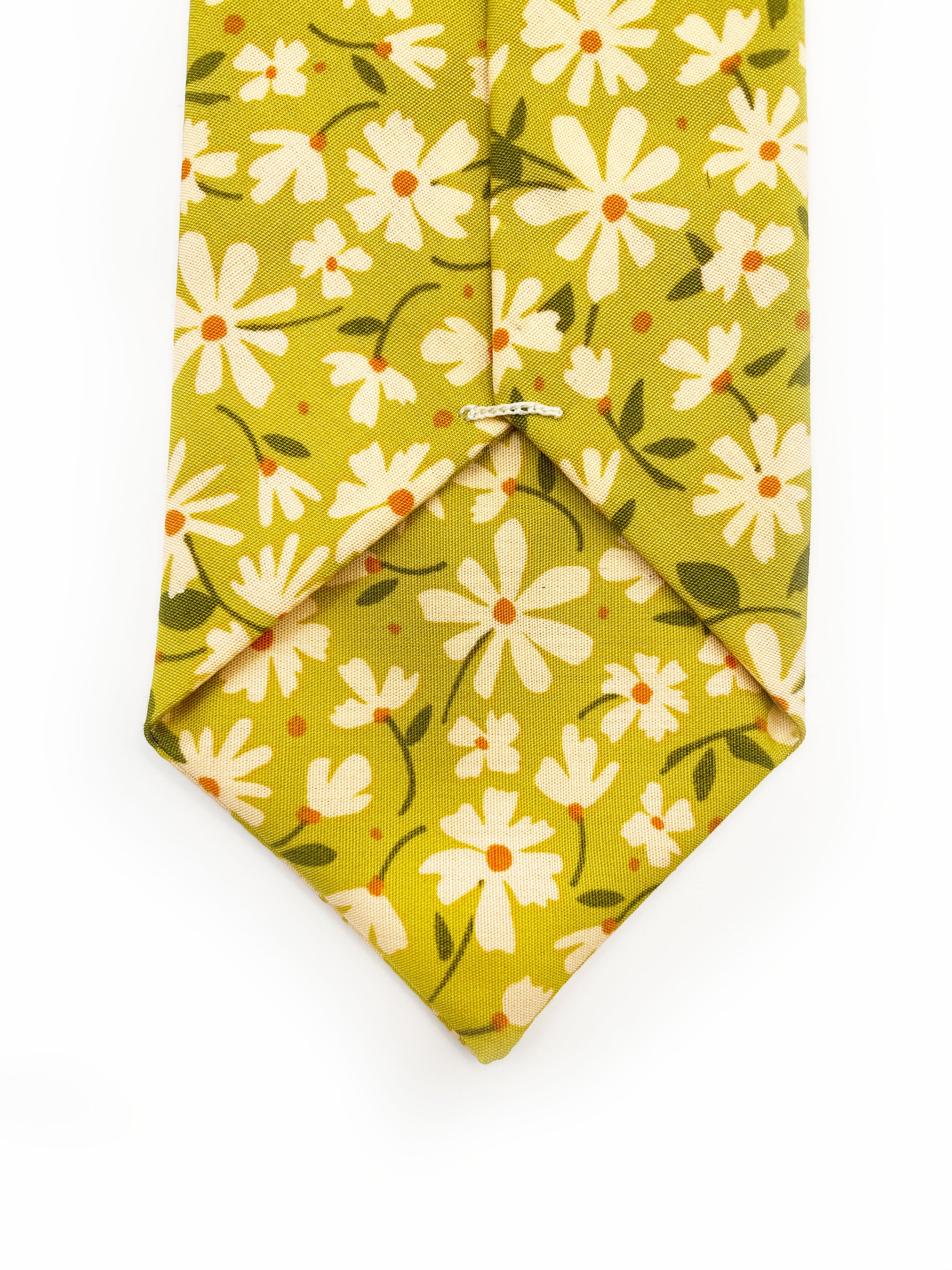 A mossy green handmade necktie with cream flowers, showcasing shades of earthy browns and pops of warm peach and blush pink.