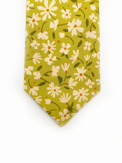 A mossy green handmade necktie with cream flowers, showcasing shades of earthy browns and pops of warm peach and blush pink.