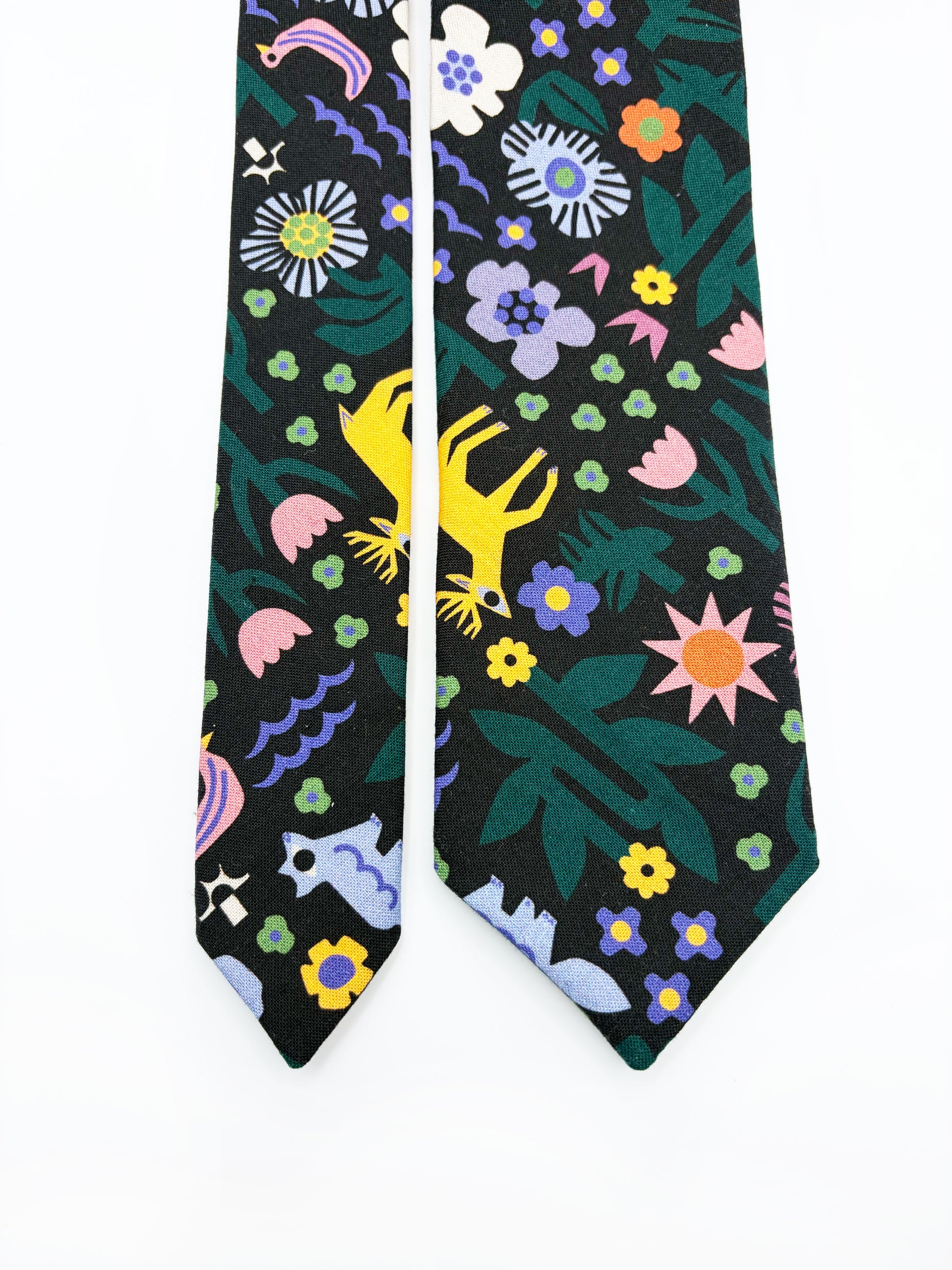 A necktie with an abstract print featuring bright forest creatures and flowers on a black background.