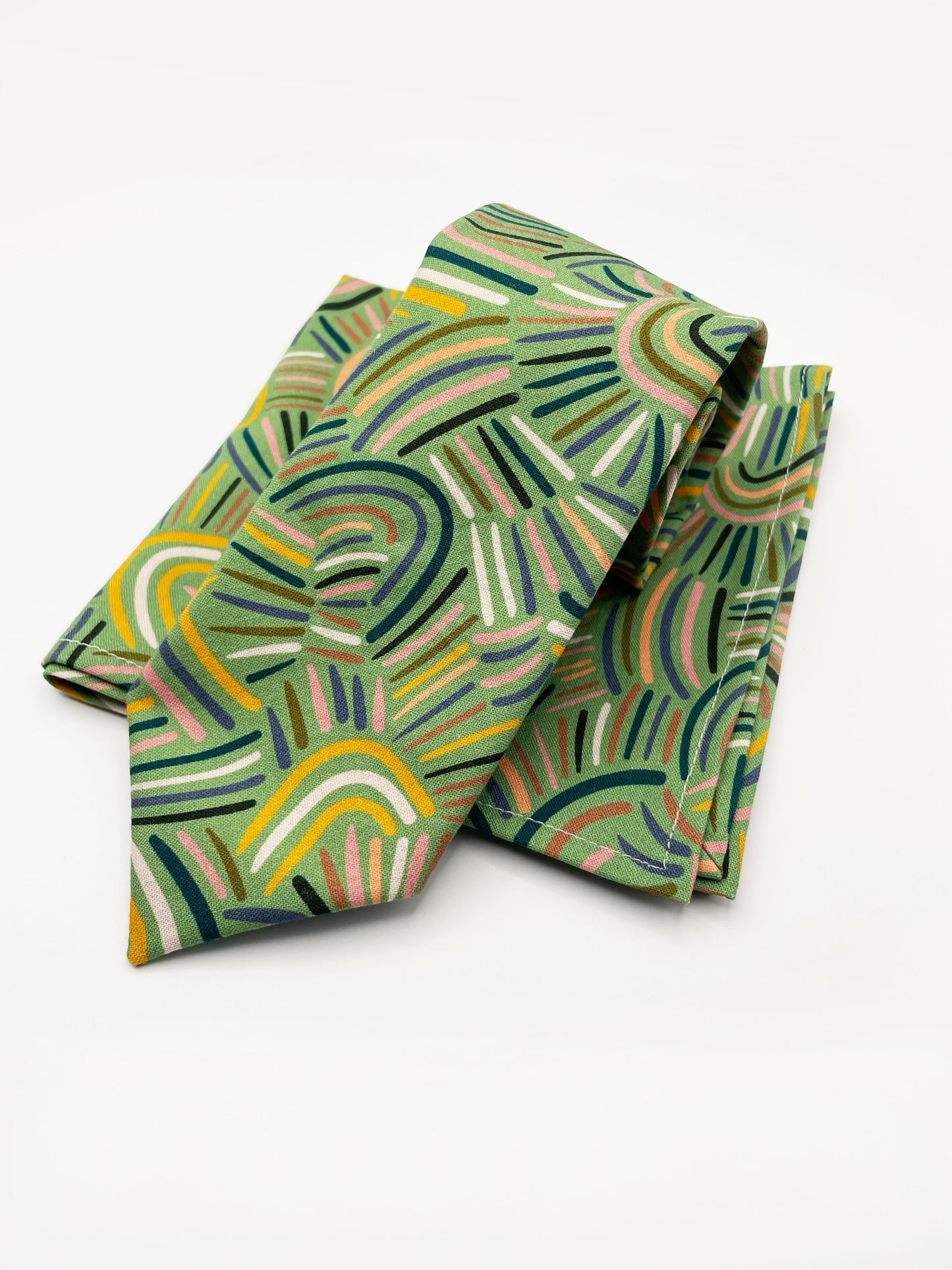 A necktie made from high-quality cotton with an abstract design inspired by desert rain patterns. The necktie is shown with a matching pocket square.