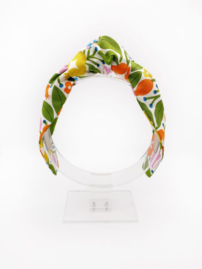 A vibrant knotted headband with bold yellow, orange, and pink flowers.