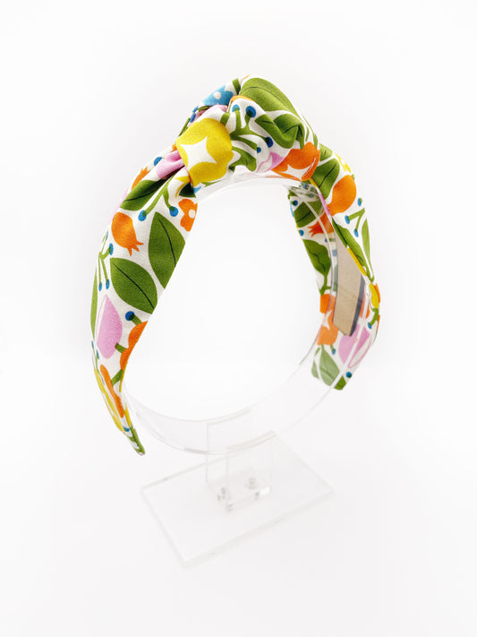 A vibrant knotted headband with bold yellow, orange, and pink flowers.