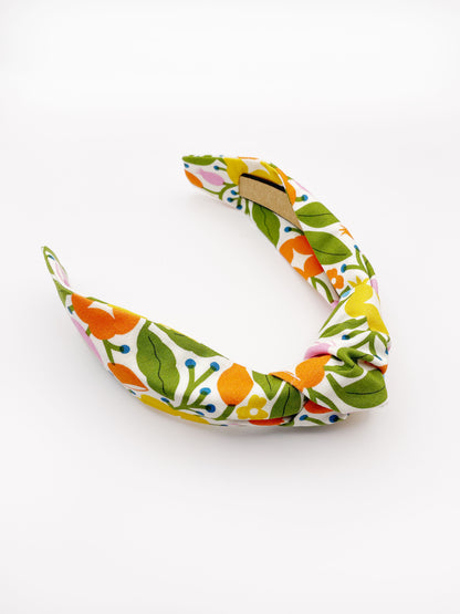 A vibrant knotted headband with bold yellow, orange, and pink flowers.