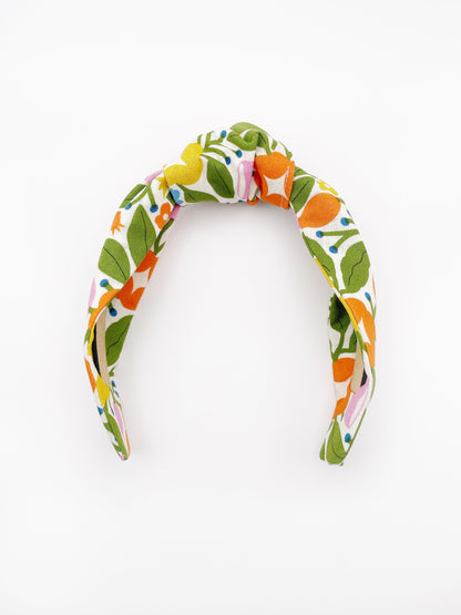 A vibrant knotted headband with bold yellow, orange, and pink flowers.