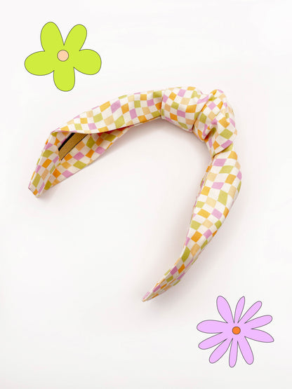 A handmade knotted headband with a pastel checkered print. 