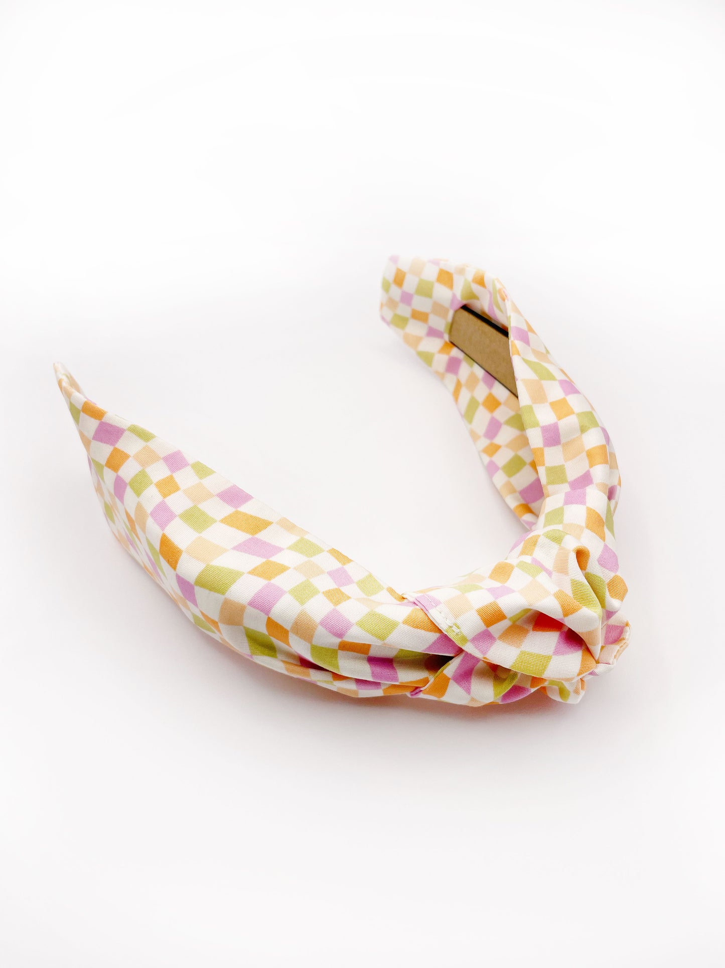 A handmade knotted headband with a pastel checkered print. 