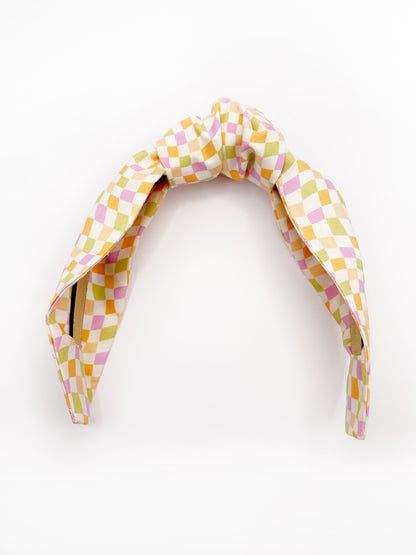 A handmade knotted headband with a pastel checkered print. 