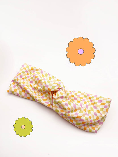 A handmade twist headband with a pastel checkered print. 