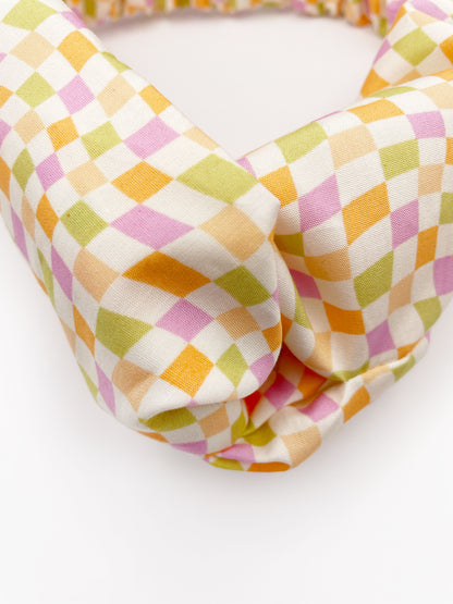 A handmade twist headband with a pastel checkered print.