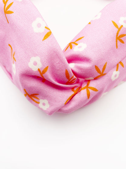 A cheerful pink twist headband with orange-stemmed flowers.