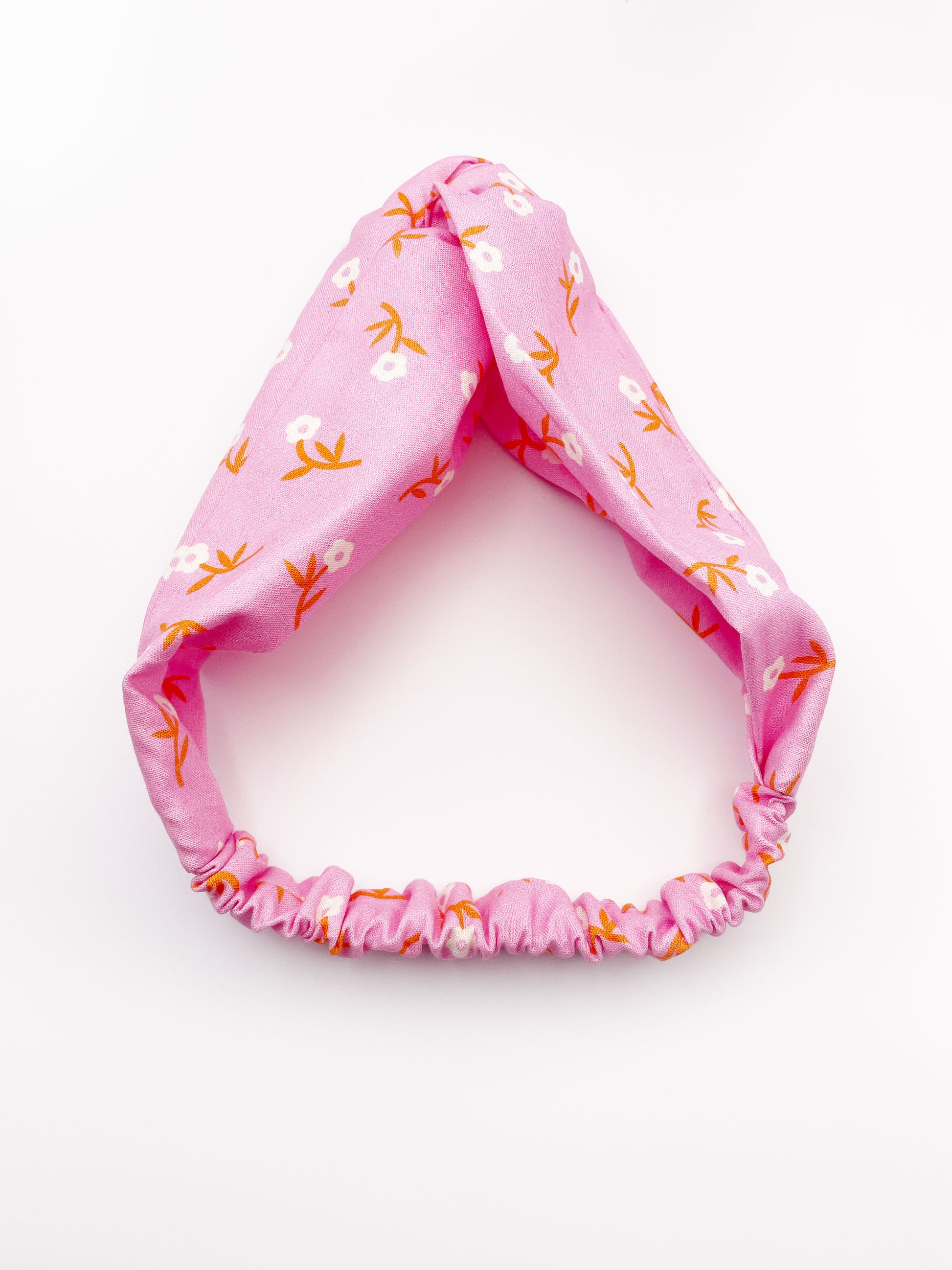 A cheerful pink twist headband with orange-stemmed flowers.