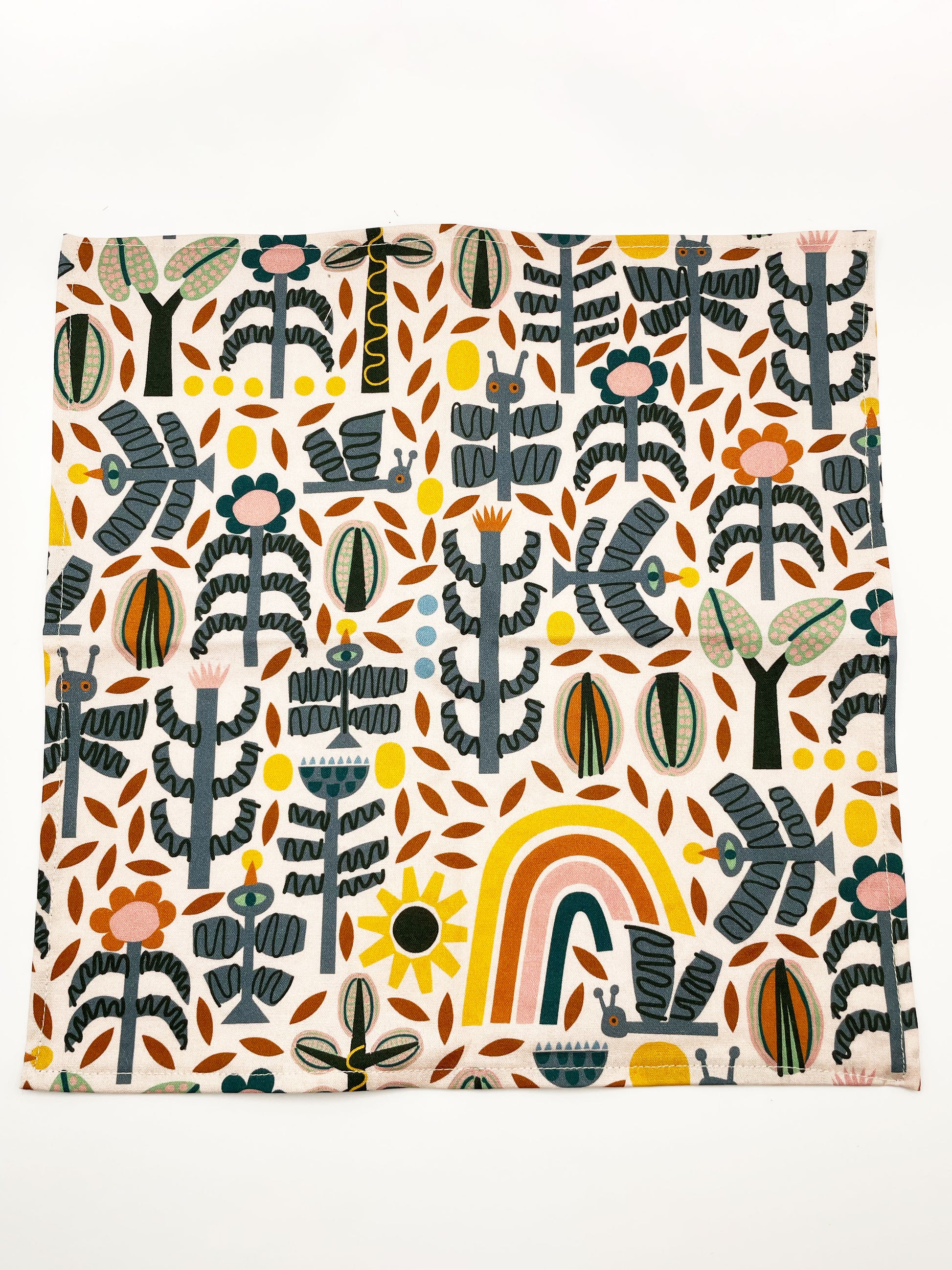 A pocket square featuring a bold nature-inspired print of bugs, plants, suns, and rainbows.