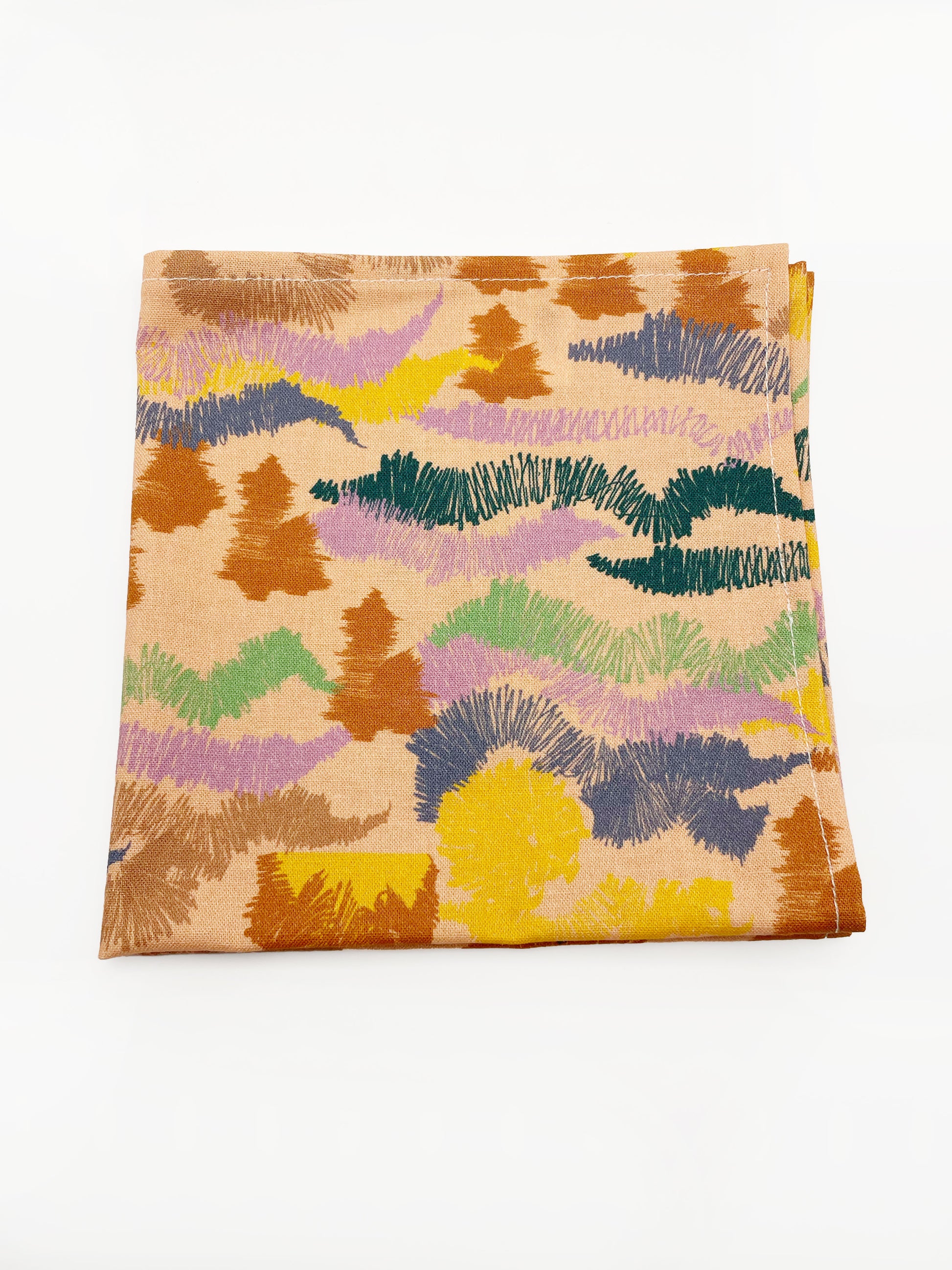 A pocket square crafted from high-quality cotton with an abstract design inspired by the rolling hills and earthy tones of the desert.