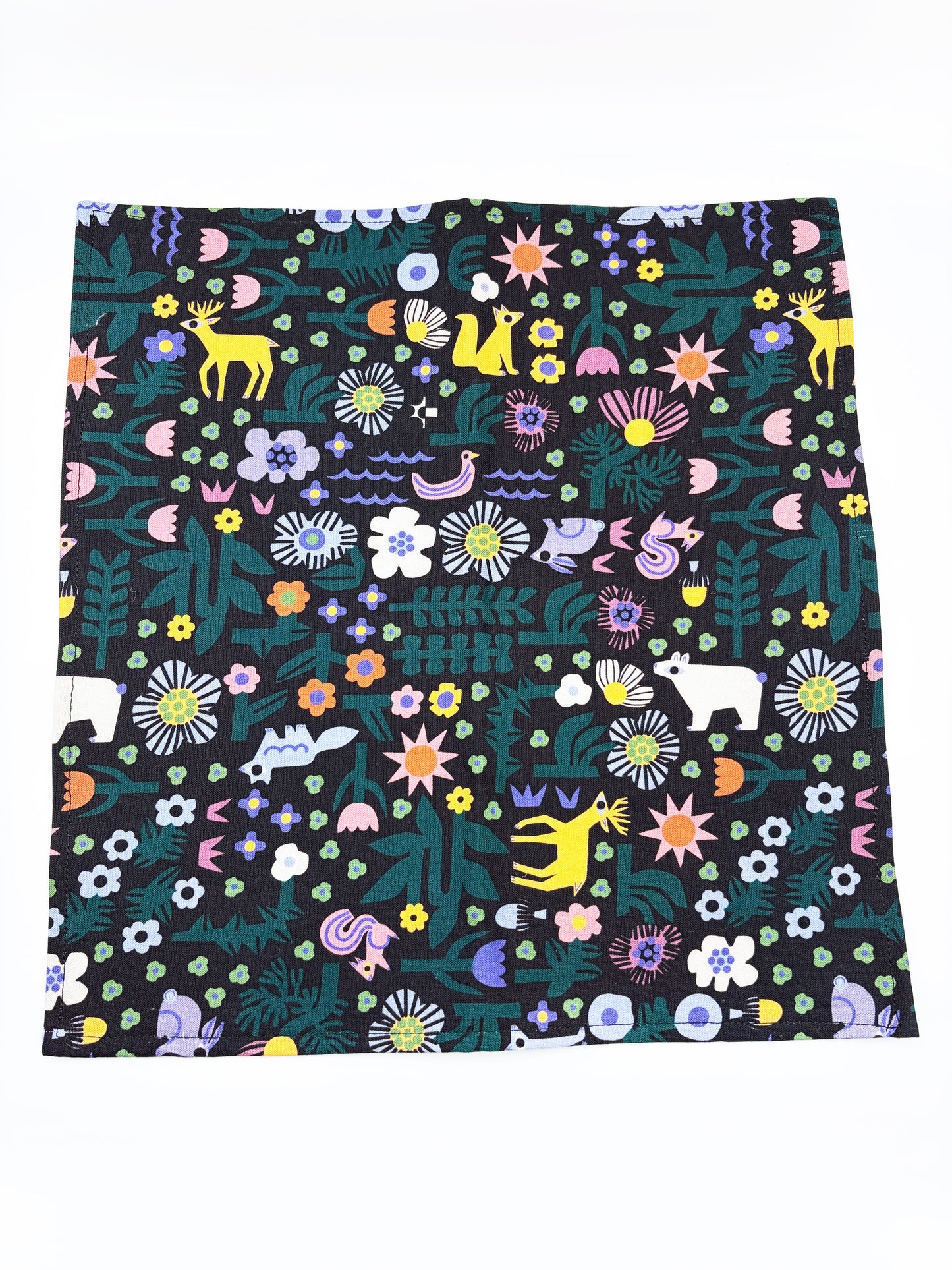 A black pocket square with a colorful abstract forest print featuring playful florals, leaves, and bright animals.