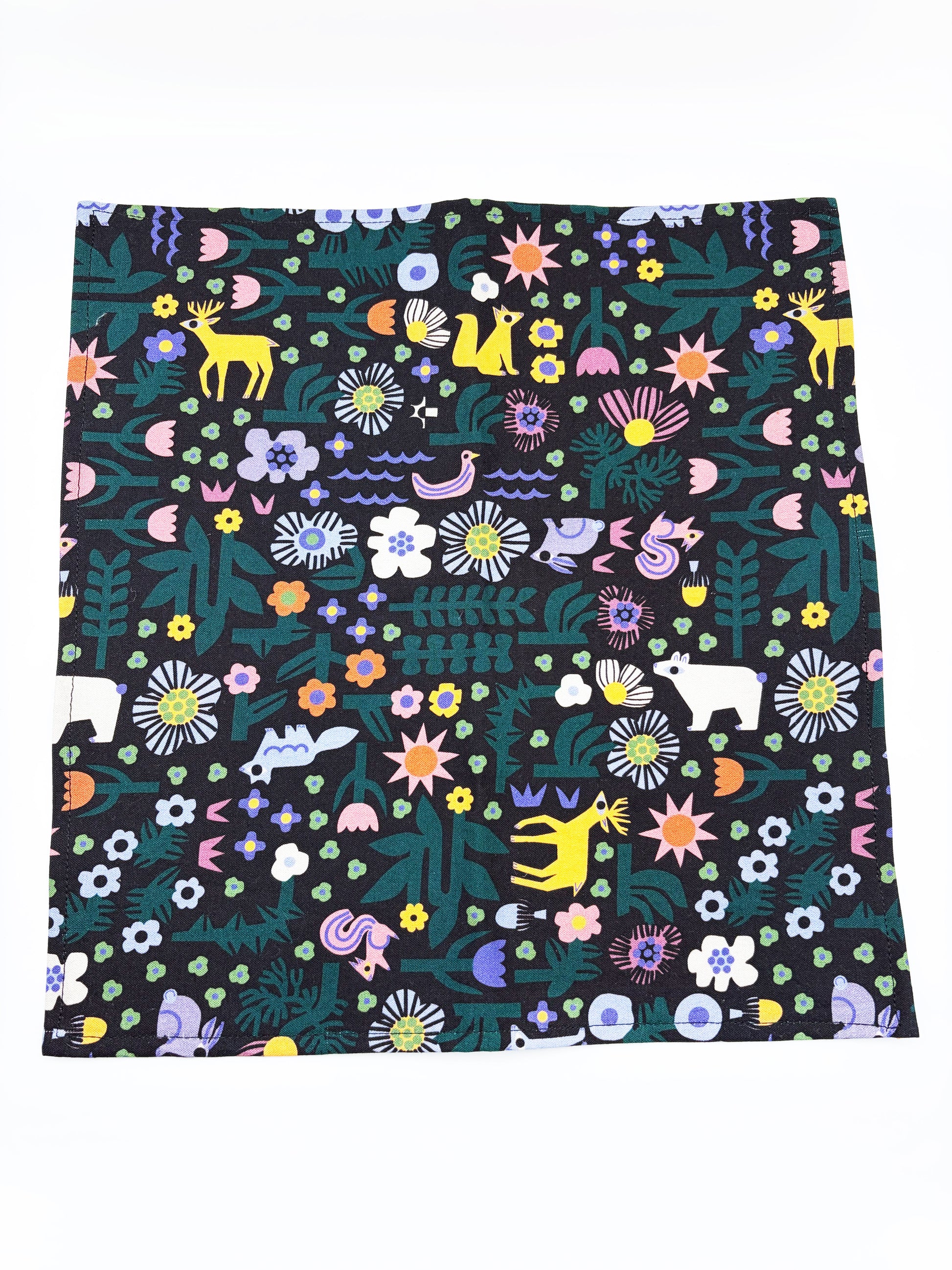 A black pocket square with a colorful abstract forest print featuring playful florals, leaves, and bright animals.