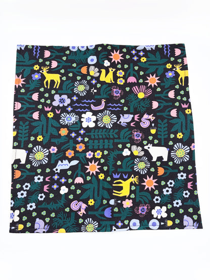 A black pocket square with a colorful abstract forest print featuring playful florals, leaves, and bright animals.