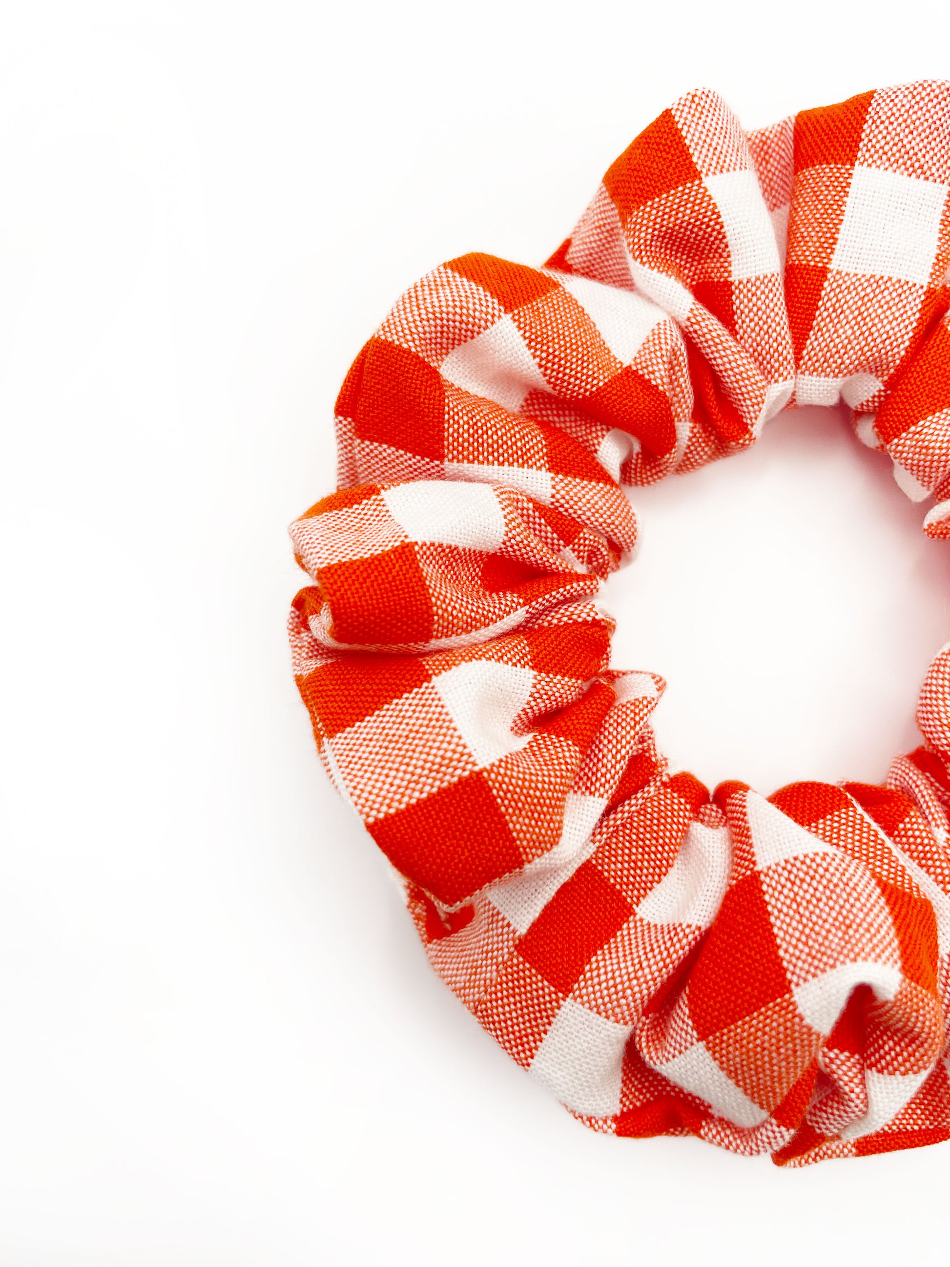 A cotton scrunchie with a vibrant red gingham plaid print.