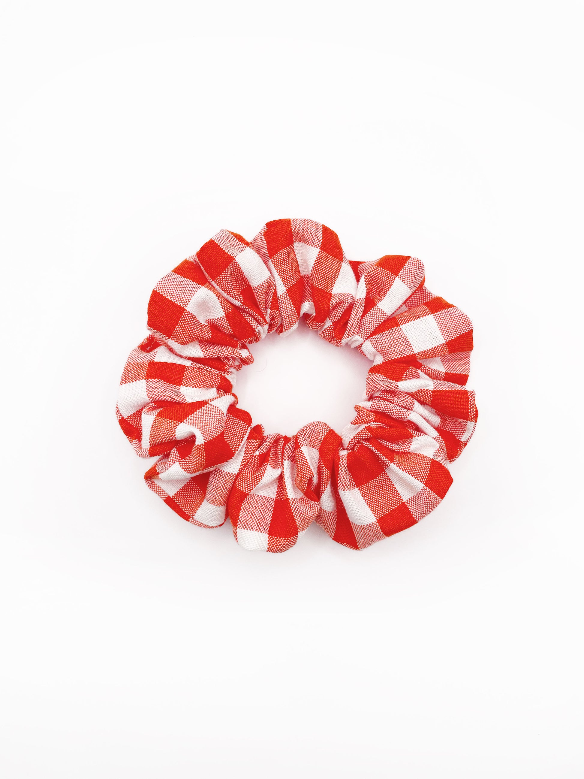 A cotton scrunchie with a vibrant red gingham plaid print.