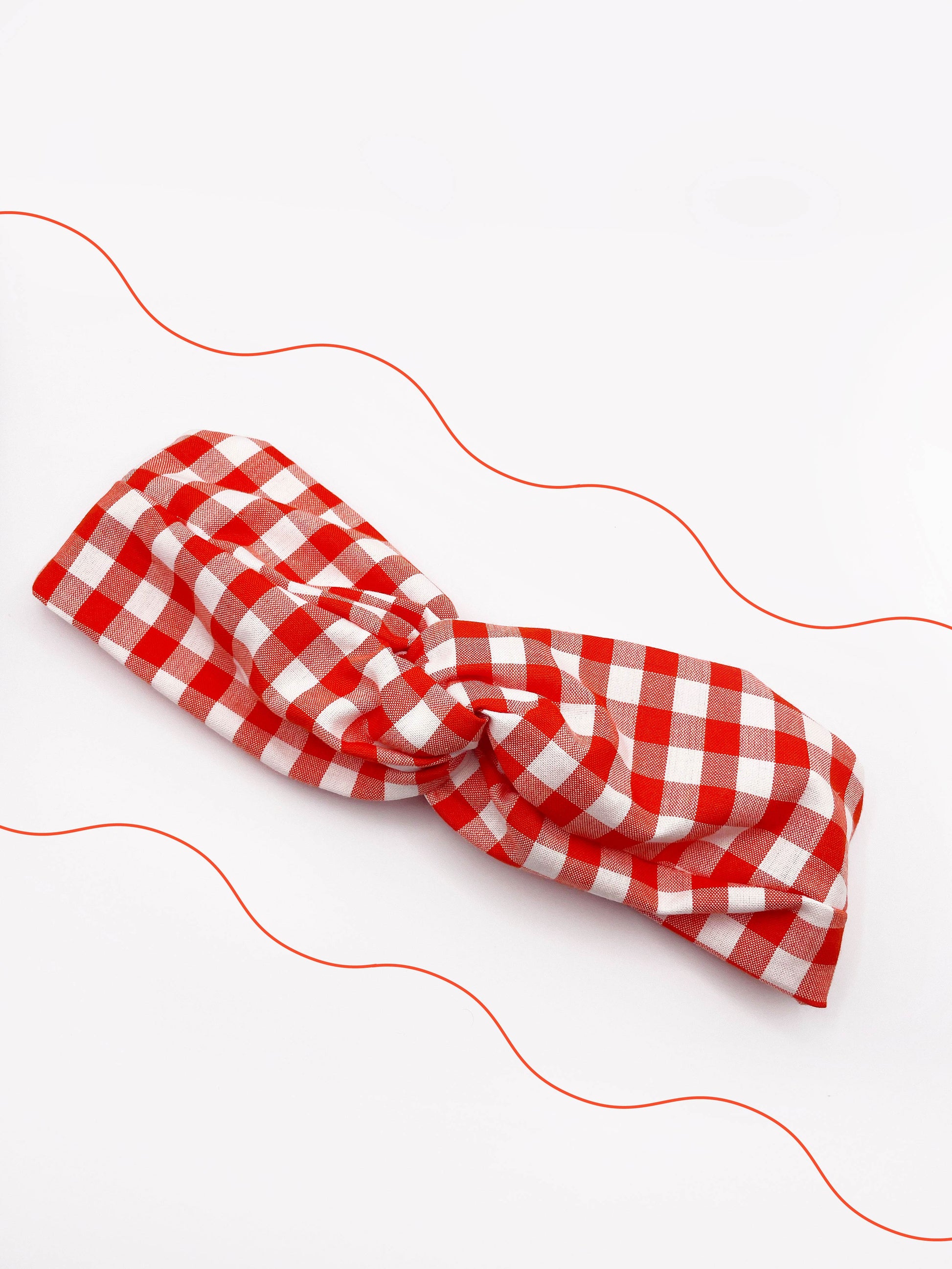 A cotton twist headband with a vibrant red gingham plaid print.