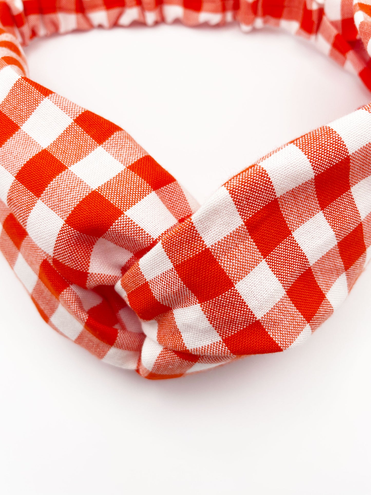 A cotton twist headband with a vibrant red gingham plaid print. 