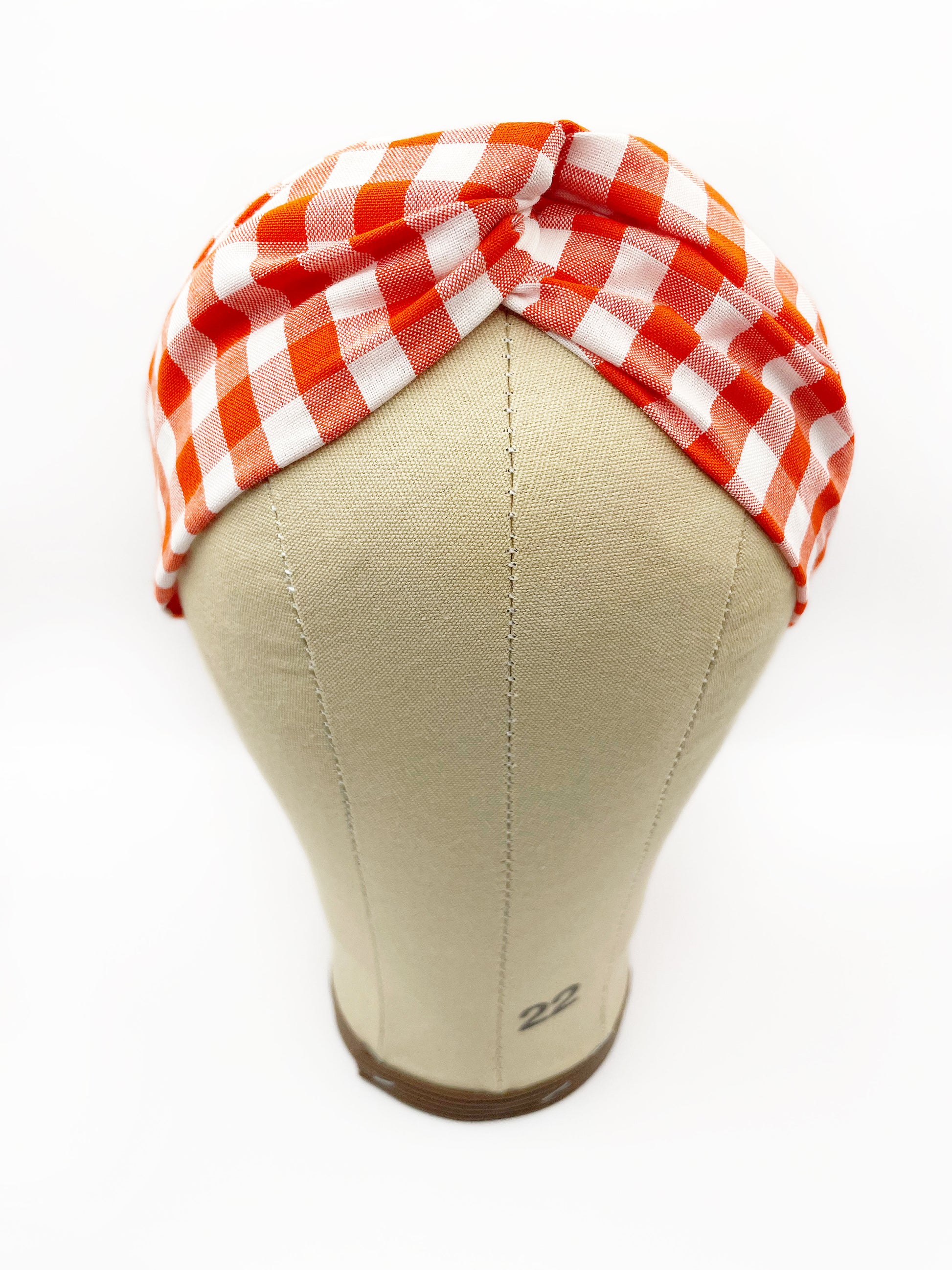 A cotton twist headband with a vibrant red gingham plaid print. The headband is displayed on a mannequin head.