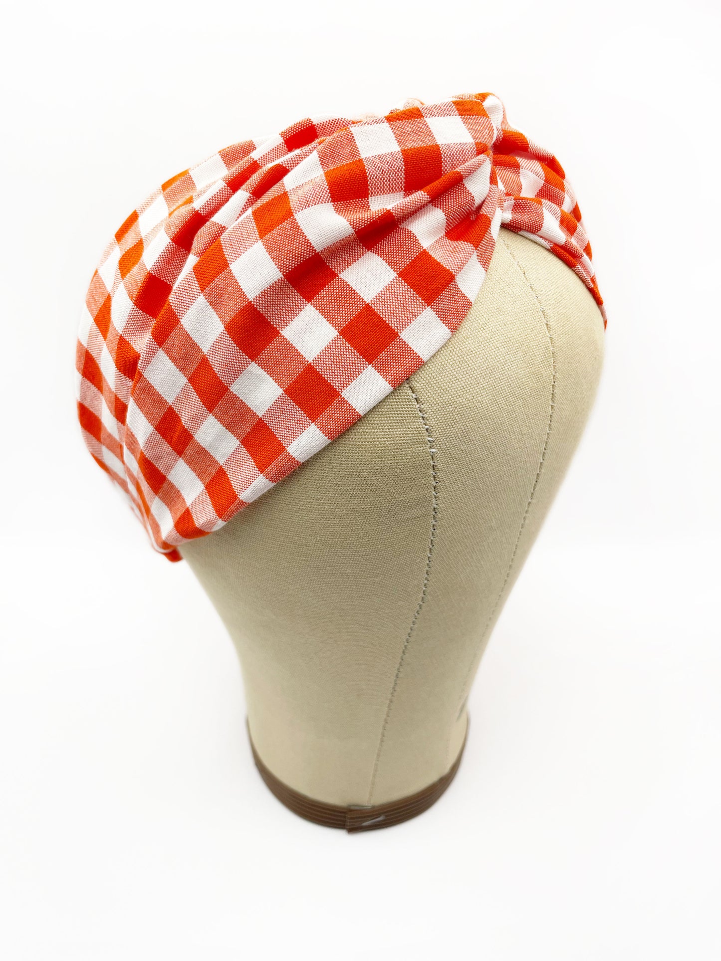 A cotton twist headband with a vibrant red gingham plaid print. The headband is displayed on a mannequin head.