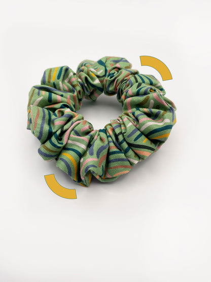 A scrunchie made from high-quality cotton with an abstract design inspired by desert rain patterns.