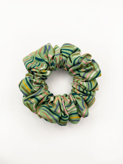 A scrunchie made from high-quality cotton with an abstract design inspired by desert rain patterns.