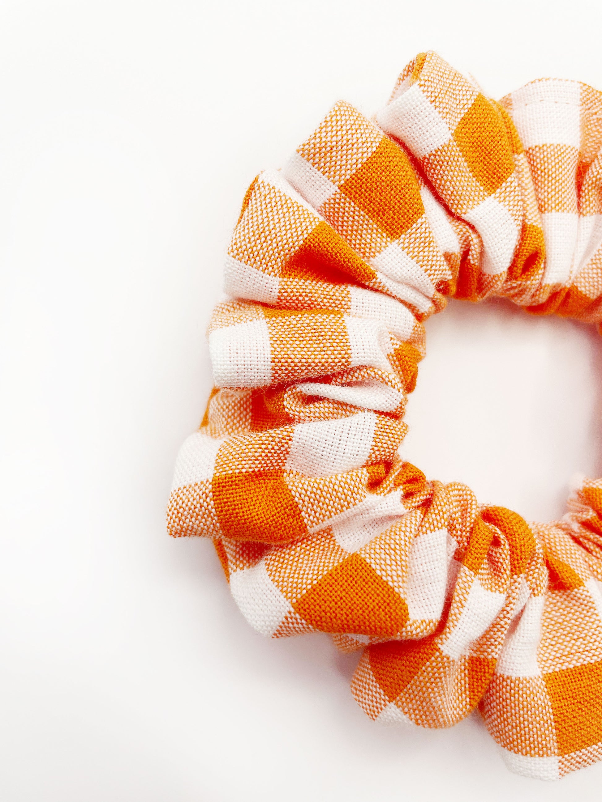 An orange and white gingham plaid scrunchie.