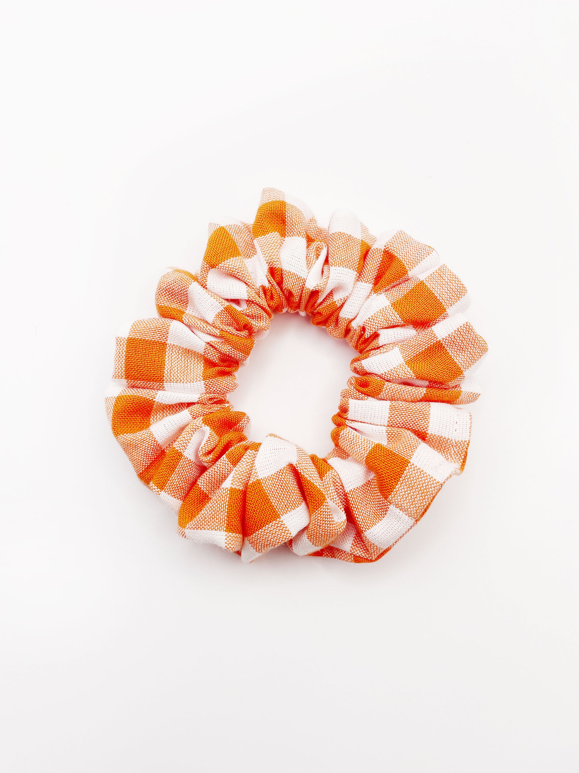 An orange and white gingham plaid scrunchie.