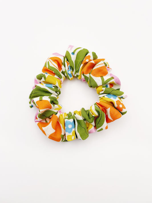 A vibrant scrunchie with bold yellow, orange, and pink flowers.
