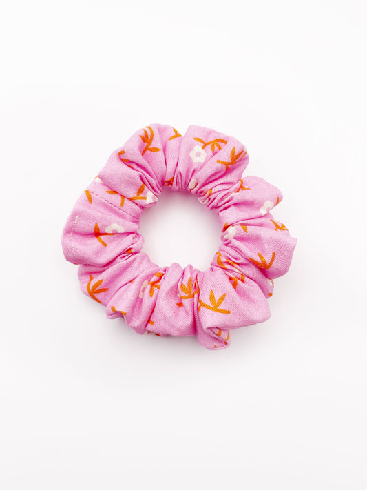 A cheerful pink scrunchie with orange-stemmed flowers.