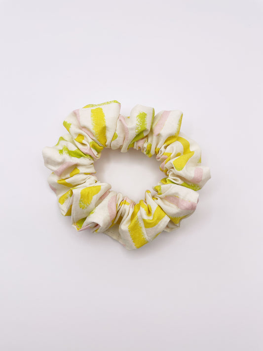 A scrunchie featuring a yellow cactus print with hints of pink and green.
