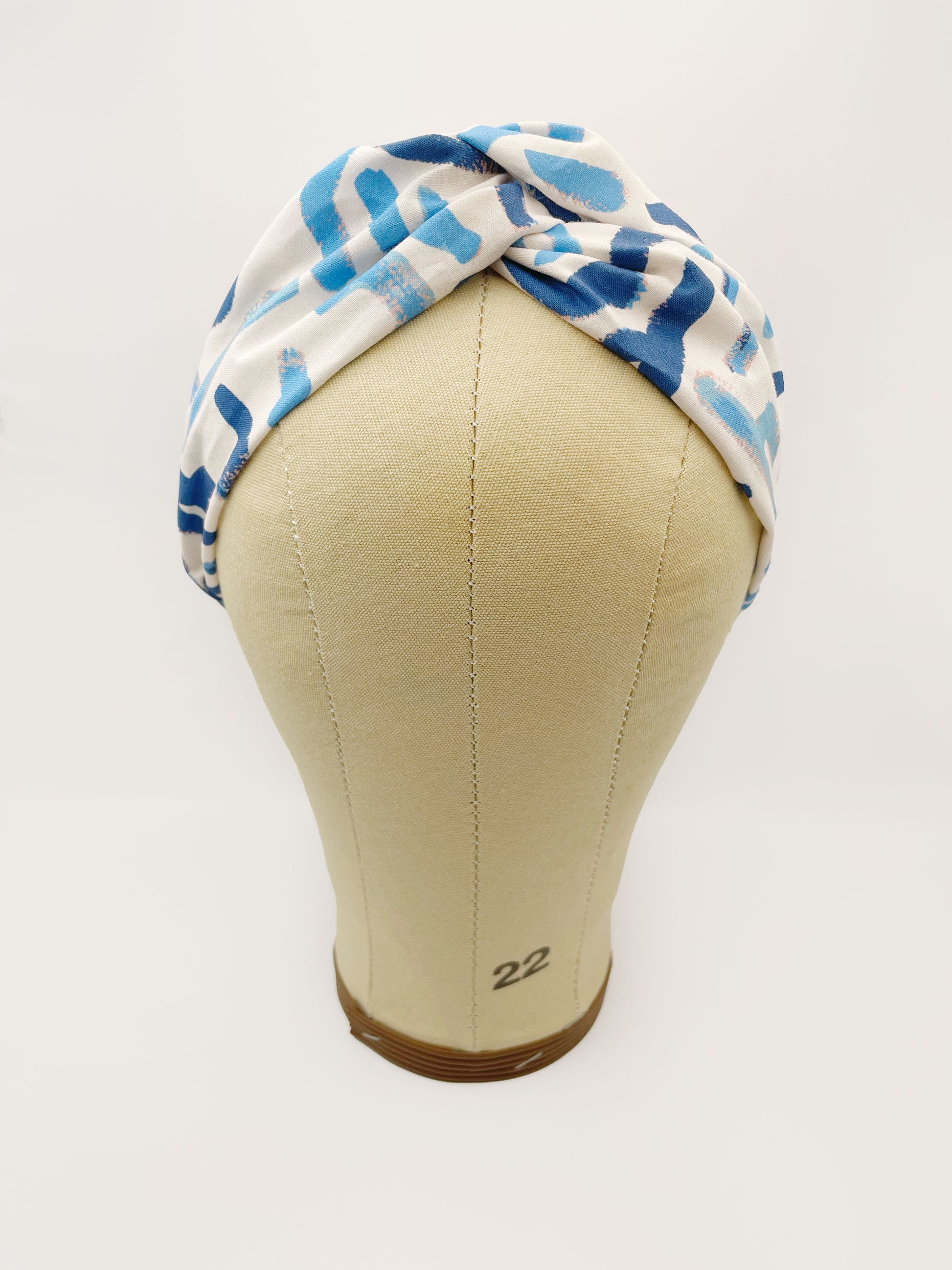 A twist headband featuring a bold blue cactus print. The headband is shown on a mannequin head.