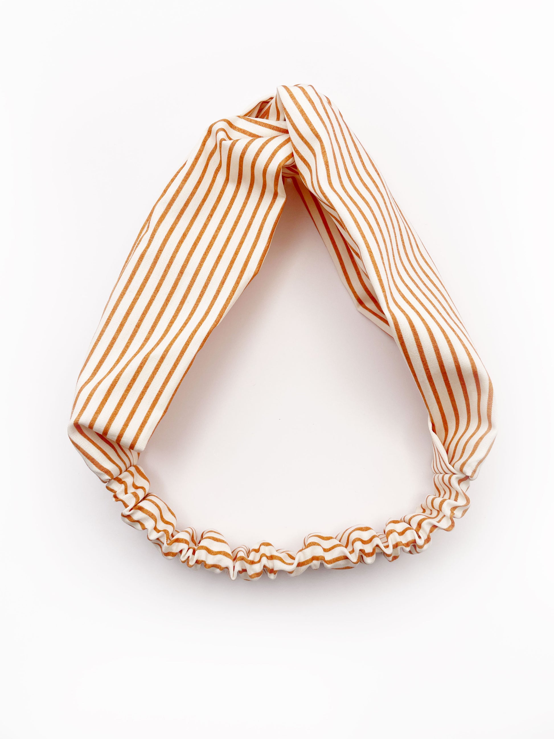 A handmade tan striped twist headband with an elastic band in the back.