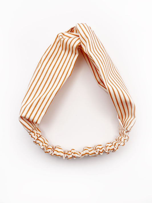 A handmade tan striped twist headband with an elastic band in the back.